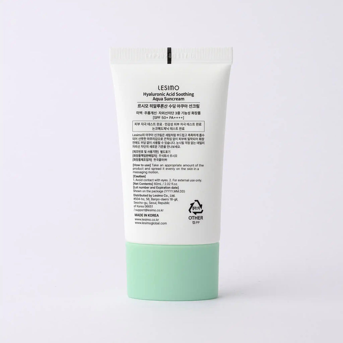 Sunscreen cream tube with green base and white label on a light gray background