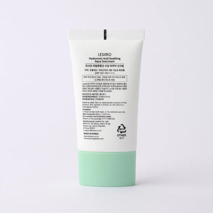 Sunscreen cream tube with green base and white label on a light gray background
